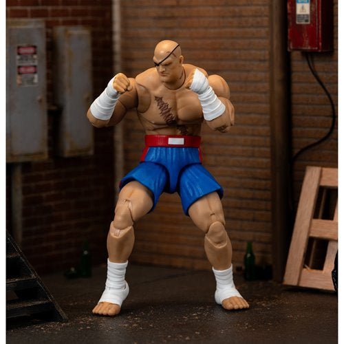 Sagat action figure posed in fighting stance in urban alley diorama setting.