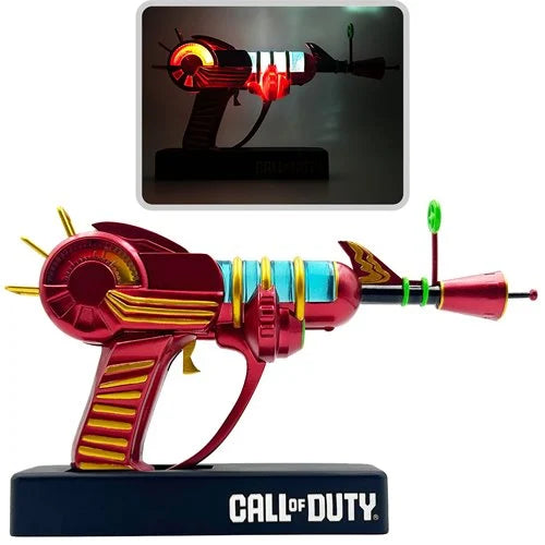 Composite image showing the Ray Gun figure lamp from Call of Duty in both standard lighting and illuminated glow-in-the-dark mode on display stand.