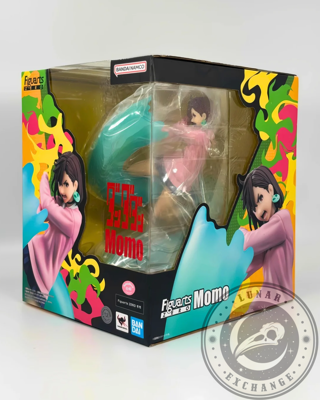 Angled side view of the FiguartsZERO Momo Ayase statue box showcasing the figure inside, with Bandai Namco branding, colorful manga-inspired graphics, and official logos.